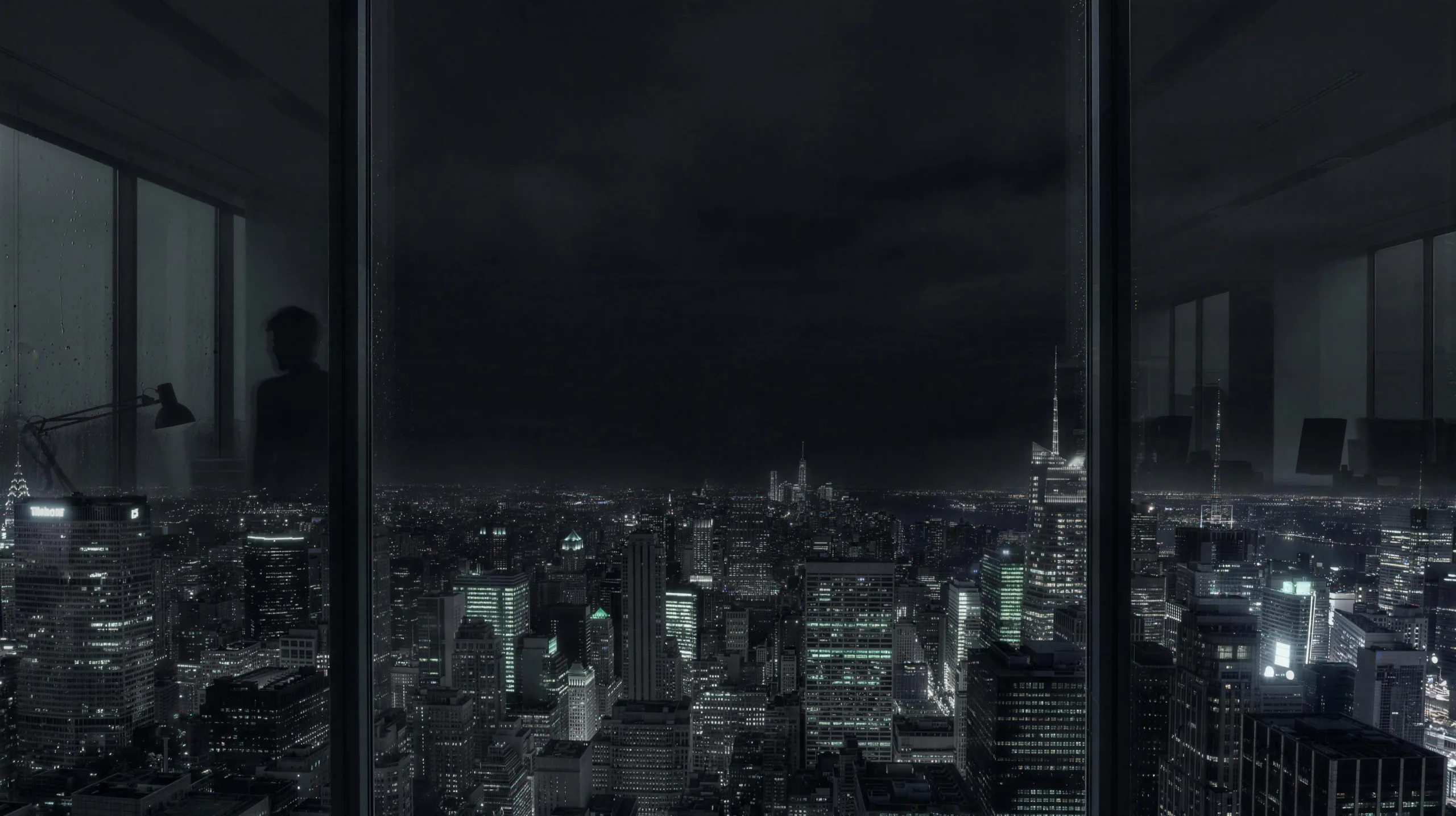 A night city skyline seen through the windows of a high-rise office
